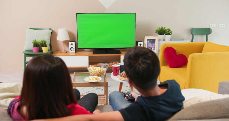 Asian young couple watching green chroma key screen TV together with food on the sofa at home Royalty-Free Stock Footage #1059110435
