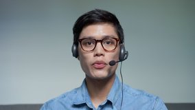 close up shot of call center employee man wear headset phone to talk and explain to customer or consult colleague via video conference online communication for new normal business technology concept