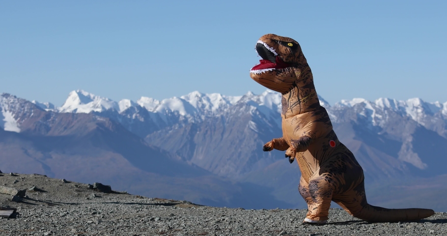 Big dinosaur doll with person inside walking in mountains in sunny summer day. Inflatable doll. Beautiful installation in the mountains with prehistoric animal. Tyrannosaurus Rex dinosaur. | Shutterstock HD Video #1059111335