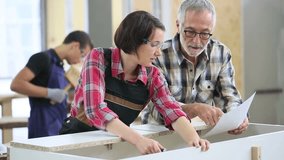 Young woman with senior craftsman in carpentry class