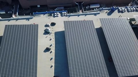 Drone descends over huge solar panels in a city.