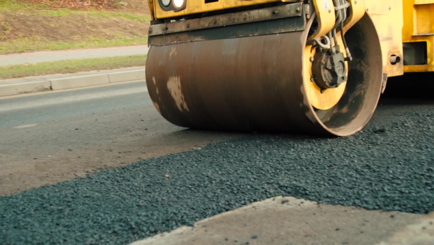 Compactor is driving over freshly poured asphalt and compresses it on the road to fix a hole Royalty-Free Stock Footage #1059112391