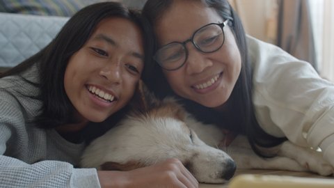 Handheld. Happy family of Asian mother and daughter, dog, taking photo selfie with mobile phone together at home 