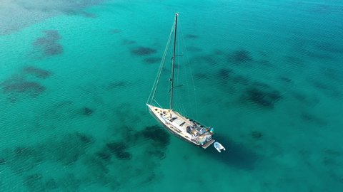 View from above, stunning aerial view of a white sailboat, floating on a turquoise, clear water. Sardinia, Italy. Sardinia is the second-largest island in the Mediterranean Sea.