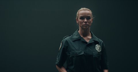 FIXED Portrait of Caucasian female police officer posing against dark background, looking into camera