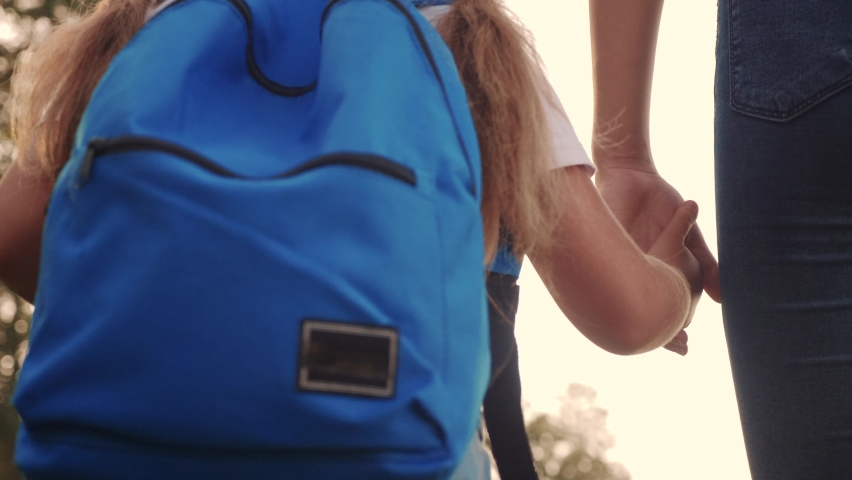 mom and daughter go to school. happy family education concept. schoolgirl lifestyle with mom and daughter go hand in hand to school on footpath in the park. little girl with a briefcase time to study Royalty-Free Stock Footage #1059127454