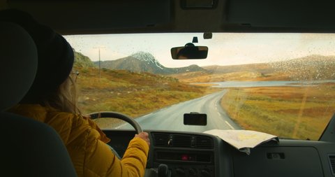 Woman drive camping van on epic mountain road. Living van life on wheels, during road trip across USA or Iceland. Female traveller drive RV van to camping site, use smartphone gps and map. Wanderlust