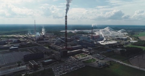 Mining and processing plant, view of pipes and smoke, mineral piles, mountains of minerlas and sand, view from height, mininпg of minerals to create chemical products, industrial building, timelapse.