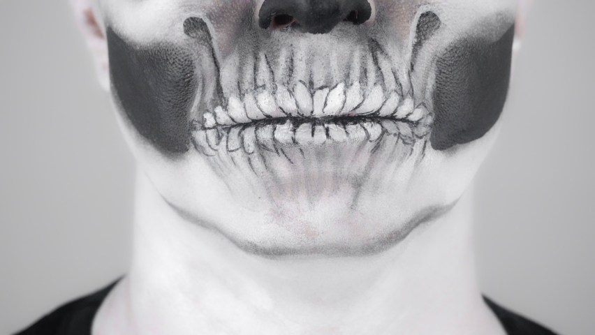 Halloween skeleton man smiling. Close-up of lips. Shooting in the studio. Gray background