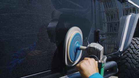 JAKARTA - Indonesia. August 31, 2020: Close up of car mechanic using an orbital polisher and wax to polish a black car door. Shot in 4k resolution