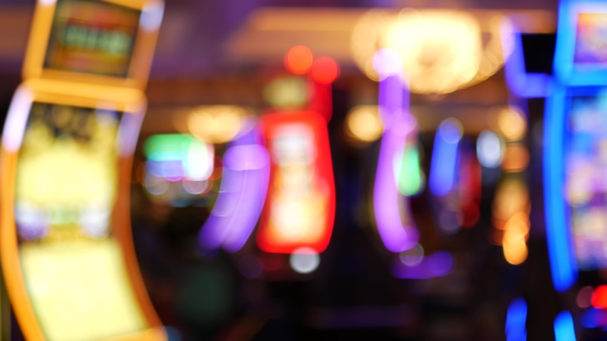Defocused slot machines glow in casino on fabulous Las Vegas Strip, USA. Blurred gambling jackpot slots in hotel near Fremont street. Illuminated neon fruit machine for risk money playing and betting. Royalty-Free Stock Footage #1059141032