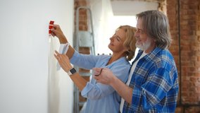 Senior couple with color swatch choosing painting for new home. Retired husband and wife selecting color for house redecoration. Elderly man and woman doing house improvement - Powered by Shutterstock - Get 15% off with code: PIKWIZARD15