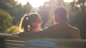 Back view of young loving couple having date on bench in park. Happy boyfriend and girlfriend enjoying time together hugging and relaxing on bench outdoors - Powered by Shutterstock - Get 15% off with code: PIKWIZARD15