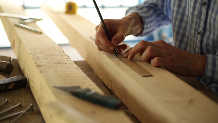 The carpenter works with wood in the workshop.