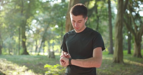Man runner using smart watch. Handsome guy tracking result after workout. Portrait of fitness man checking result. Sport man looking smart watch.
