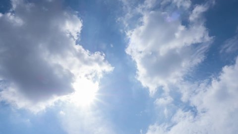 Beautiful sun bright and rays flare vibrant sunlight, sunbeam with white fluffy clouds at midday sunshine day in sunny summer season, clean energy renewable energy sky background concept.