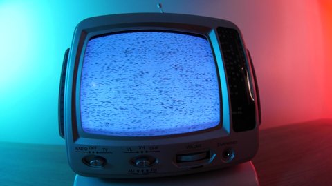 Vintage CRT TV screen broken showing static noise. 80s 90s retro small television with blue and red lights in the background.