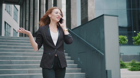 Happy business woman walking speaking on phone down stairs on urban street near city center. Working financial adult manager. Focused female workplace slow motion.