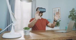 Medium plan of young man wearing virtual reality headset using gestures to control smart connected home 360 video immersive concept. Concept of futuristic remote work, vr reality