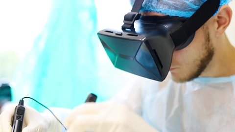 male surgeon performs an operation on a patient in virtual reality. Controls the arms of robotic manipulators. Remote treatment of cancer and infected patients. Modern technologies in medicine.