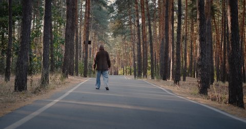 Drunk homeless man walks on the road in the park