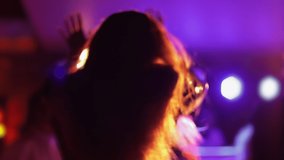 Blurred video of a dancing girl with her hair down at a party in the rays of concert lights.