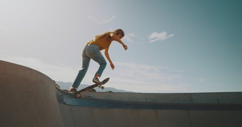 Young woman skateboarding, carving the bowl at the park
