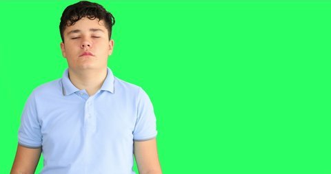 Teenage boy with serious face at green screen background