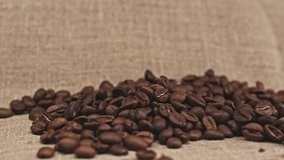 Roasted coffee beans fall down. Dark coffee grains fall down. Close up beans of coffee.
