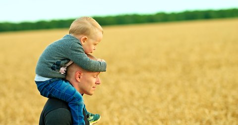 Happy child sits on dad's shoulders and plays. Young father carefully carries his son on his shoulders, happy fatherhood. Family values. 4k, ProRes