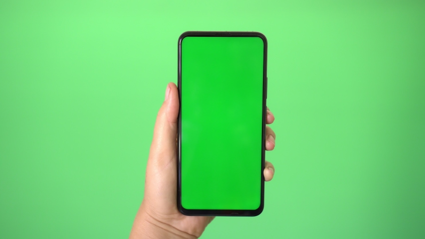 Woman's hand holding a mobile telephone with a vertical green screen in tram chroma key smartphone technology cell phone touch message | Shutterstock HD Video #1059168881