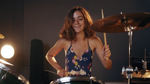 Music Production Studio. Creative world. Hispanic woman playing drums in the rehearsal space. Brunette female person with afro hair learning new musical lessons.