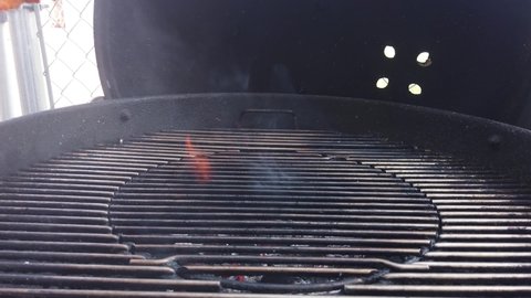 Placing a marinated wild salmon steak on the barbecue and watching it flame up