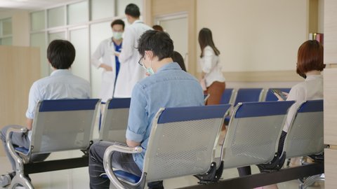 Busy hospital lobby with busy nurse, older patient on wheelchair, rear view sick patient sit, wait and cough, doctors walking at reception wearing medical mask healthcare concept.