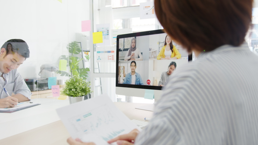 Asia businesspeople using desktop talk to colleagues discussing business brainstorm about plan in video call meeting in new normal office. Lifestyle social distancing and work after corona virus. | Shutterstock HD Video #1059172700