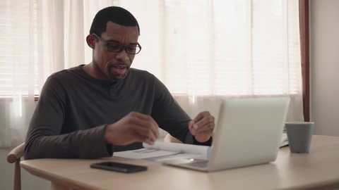 African American creative designer man making video call meeting and working on laptop at home. Black Freelancer male explaining discussing with business partner team or colleague or client 