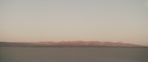 Sunlit mountains over desert lake in evening