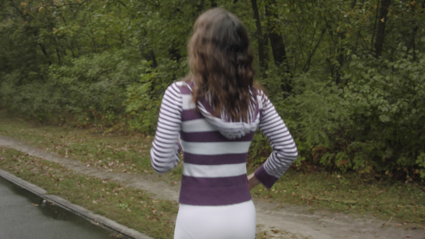 Woman doing morning jogging through the forest after rain. A woman runs along the road in the forest.