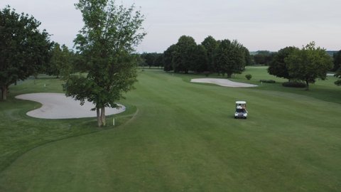 Aerial of married couple in golf cart driving around a golf course after sunset
