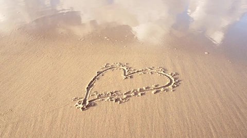 Drawn Heart Shape on the sand in the beach, washed away by soft waves. Broken Heart Concept.