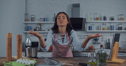 Woman gesturing and talking at camera while cooking in kitchen