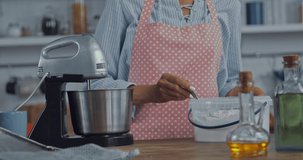 Cropped view of woman adding flour in food processor in kitchen