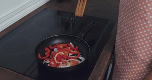 Cropped view of woman frying vegetables on stove