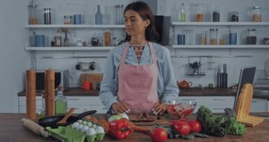 Woman seasoning salad near vegetables in kitchen