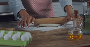 Cropped view of woman rolling dough near ingredients in kitchen