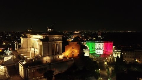 ROME, THE ITALIAN FLAG PROJECTED ON THE FACADE OF THE CAMPIDOGLIO WITH A VIEW ON THE IMPERIAL FORES, COLOSSEUM AND ALTAR OF THE PATRIA. NIGHT SHOOTING WITH DRONE