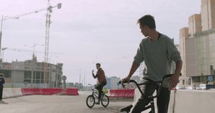 Extreme bmx guys bikers meeting in sunny city street in summer. Cool young friends riders have fun with bicycles. Urban outdoors lifestyle 4k raw video footage