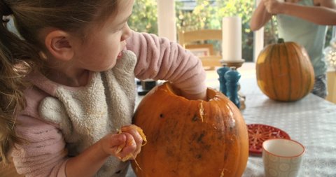 Young girl carving a jack o' lantern and pulling all its slimy insides out. Halloween party preparation