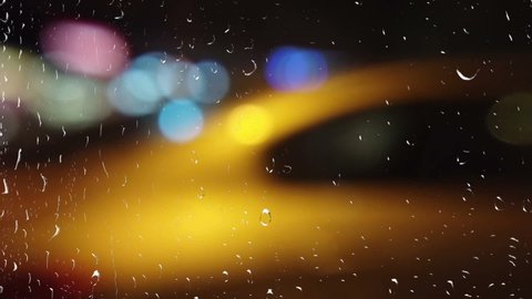 A car in a night town. View from the window during the rain. Out of focus.