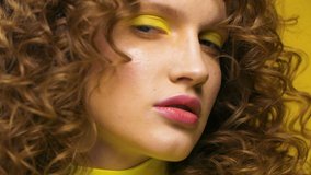 Close up Portrait of Woman’s Face, female Model looking at Camera, having nice Appearance. Demonstrating Professional Makeup. Yellow eyeshadow and pink Glamorous lips. Slow Motion Video Shot.